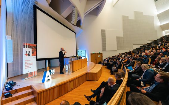 People sitting in a big seminar hall, Department Head Jens Schmidt opening the seminar on stage. 