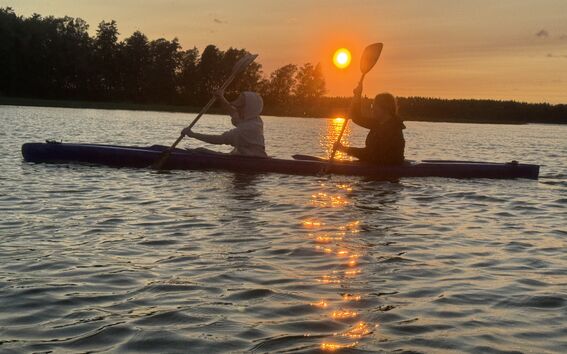 two students kayaking in the sunset