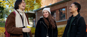 Three students, Olia in the middle, chatting and laughing in front of a student housing building.