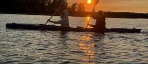 two students kayaking in the sunset