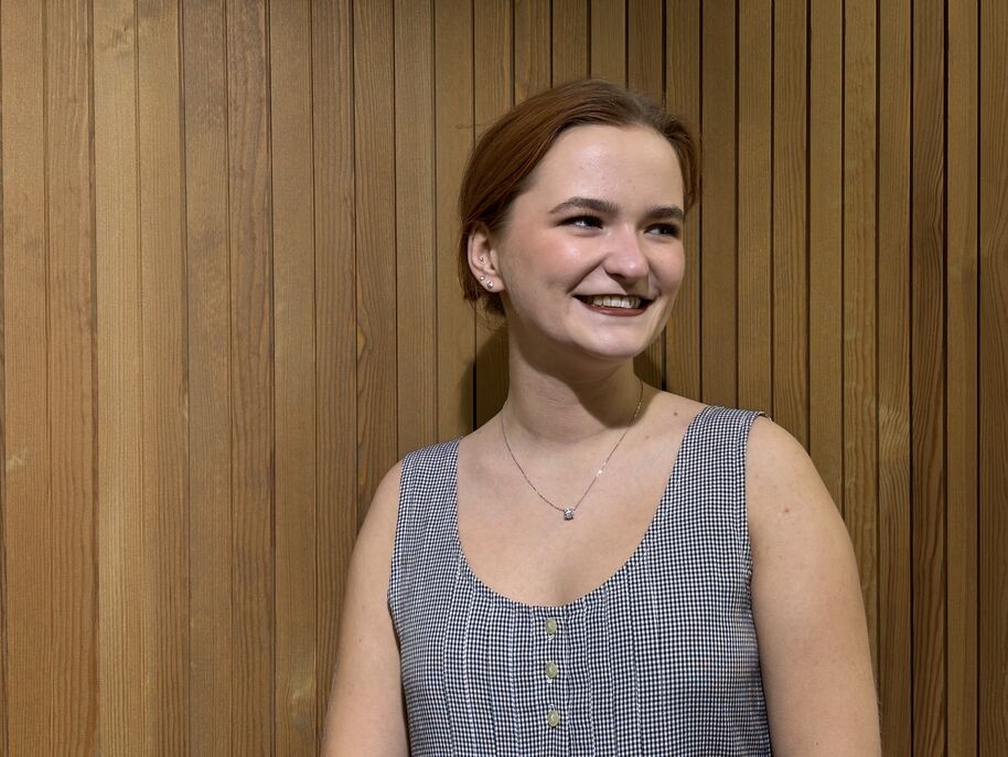 Oona Paananen puuseinän edustalla.