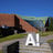 Kuvassa suuri valkoinen Aalto-yliopiston logo on punatiilisen kookkaan rakennuksen edessä portailla.