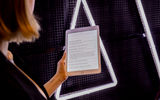 Woman holding up an iPad in front of a large Aalto logo.