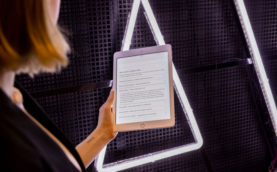 Woman holding up an iPad in front of a large Aalto logo.