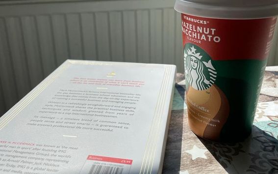 Student's study setup with a book and takeaway coffee