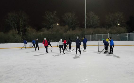 Students playing ice hockey in an ice rink.