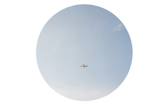 Round cropped image of sky with aeroplane in distance