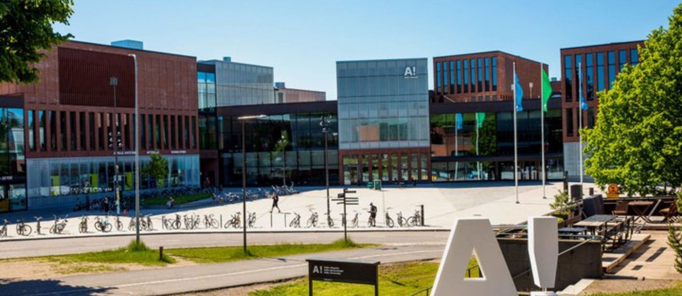 View of A-Block in the summer with the Aalto University logo in the front