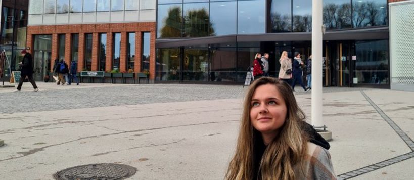 Milica sitting in front of the School of Arts, Design and Architecture