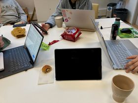 Friends studying togeter with laptops and snacks on a table.