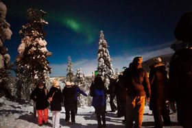 Students admiring the northern lights on a snowy hill.
